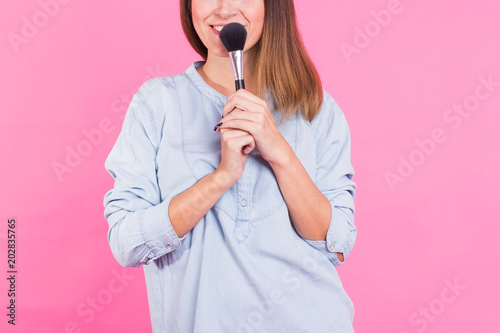 Closeup of professional makeup artist with brushes on pink background