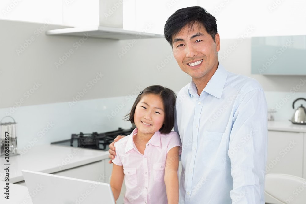 Smiling father and young daughter with laptop in kitchen Smiling father and young daughter with laptop in kitchen