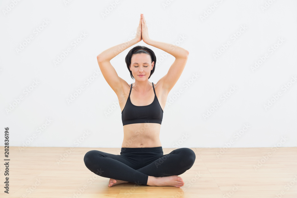 Woman in lotus pose with eyes closed at fitness studio Woman in lotus pose with eyes closed at fitness studio