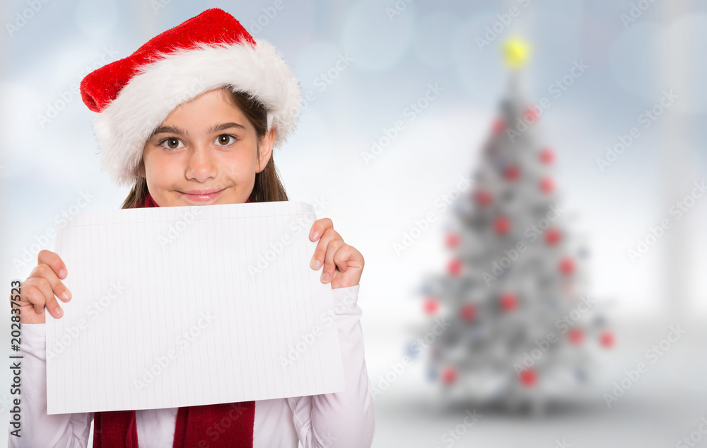 Festive little girl showing card against blurry christmas tree in room