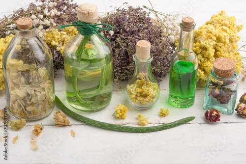 Aromatic oil  aromatic herbs in glass bottles  on a wooden background. The concept of body care and beauty