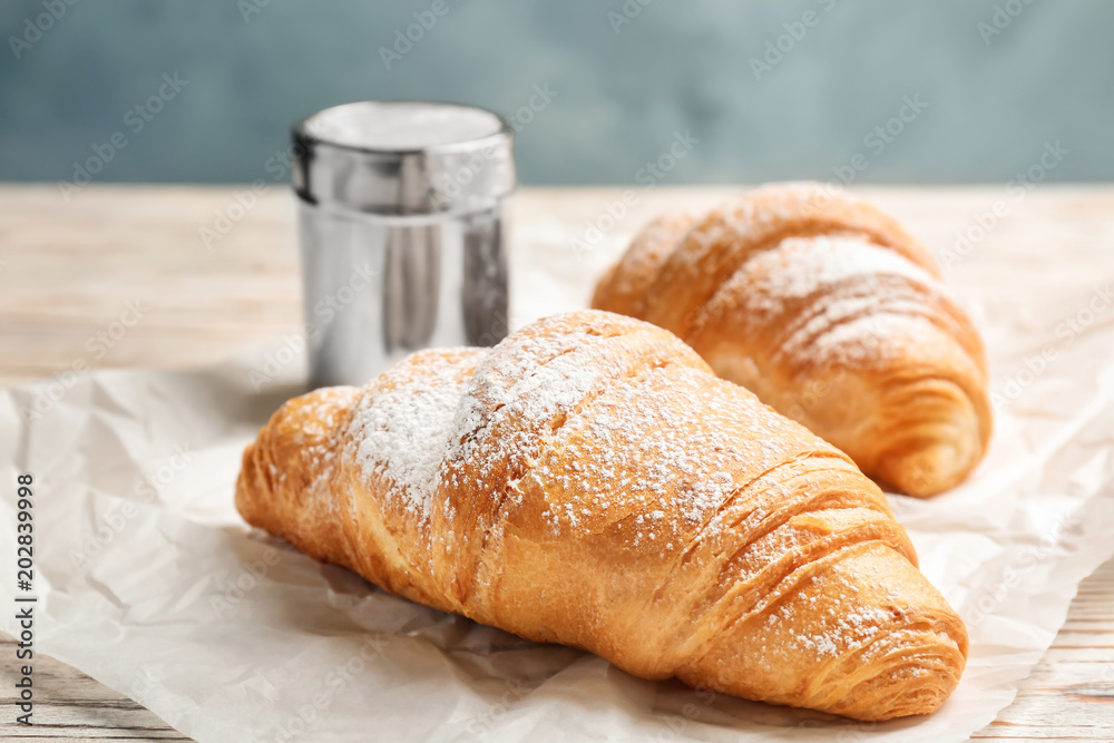 Tasty croissants with sugar powder on table