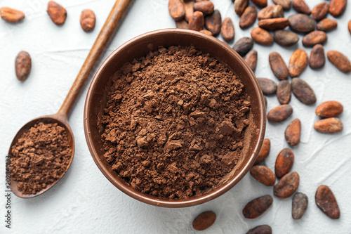 Flat lay composition with cocoa powder and beans on light background