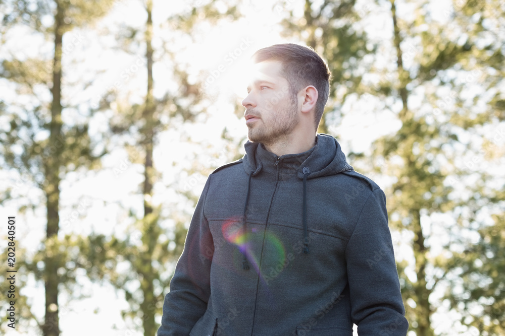Man in pullover standing in forest against trees Man in pullover standing in forest against trees