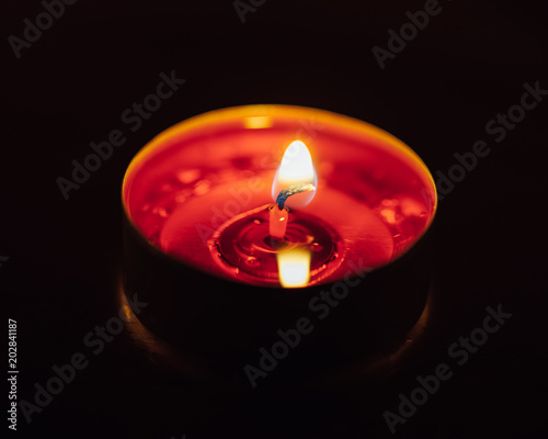burning red tealight candle, closeup view