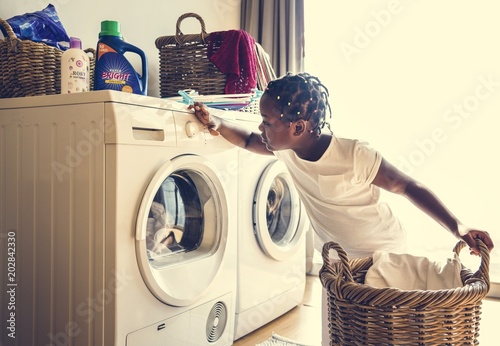 Young teen girl washing clothes using washing machine photo