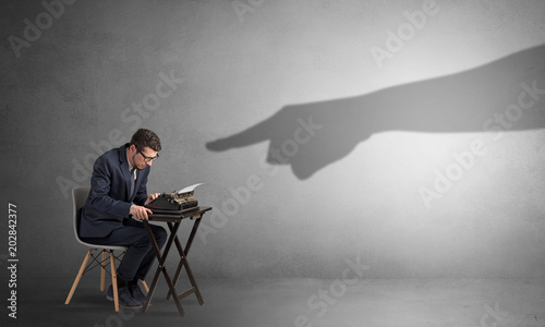 Shadow hand pointing at a small afraid worker
