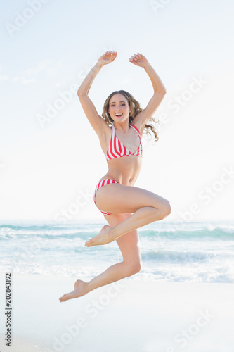 Young woman jumping on the beach wearing a red bikini © WavebreakmediaMicro
