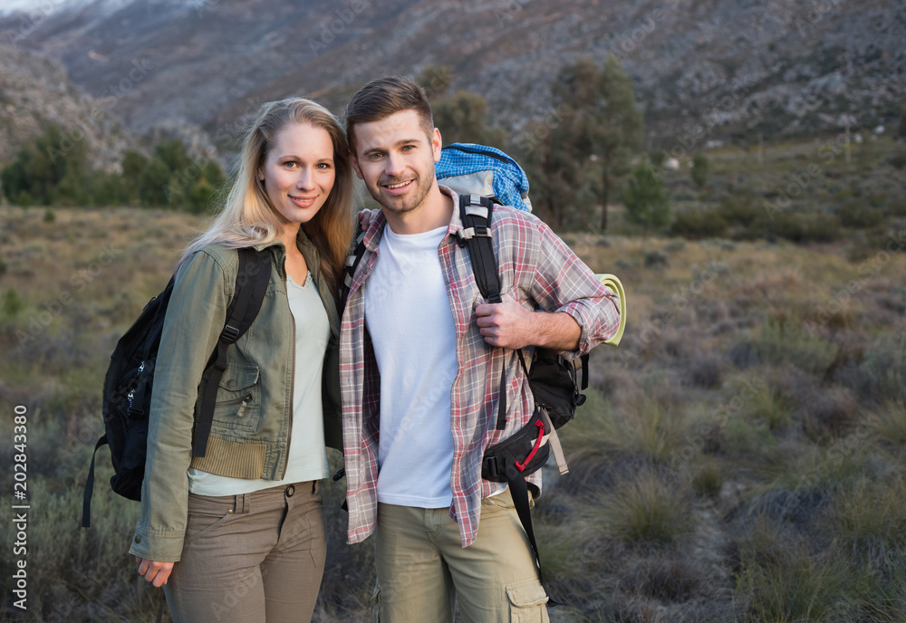 Couple with backpacks standing on forest landscape