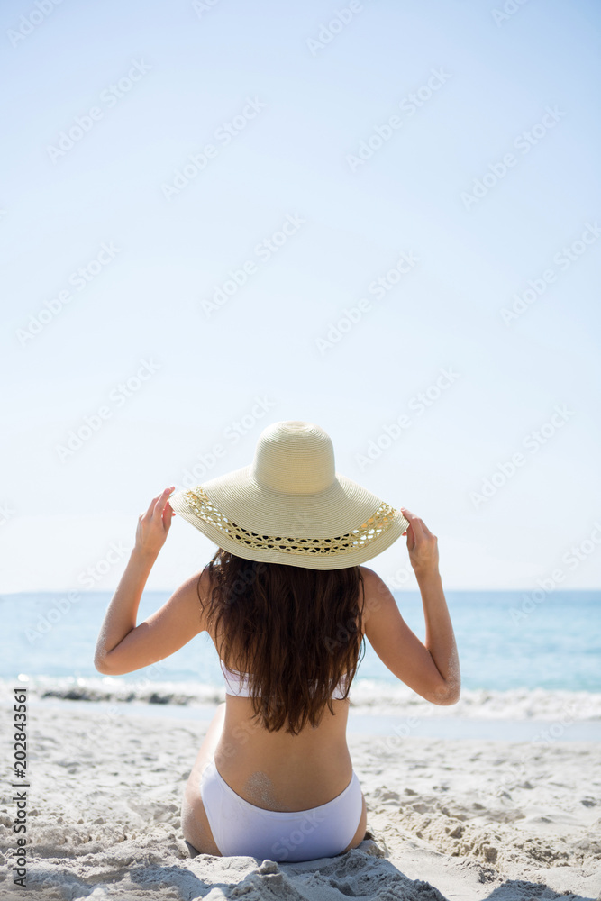 Rear view of woman in bikini holding sun hat