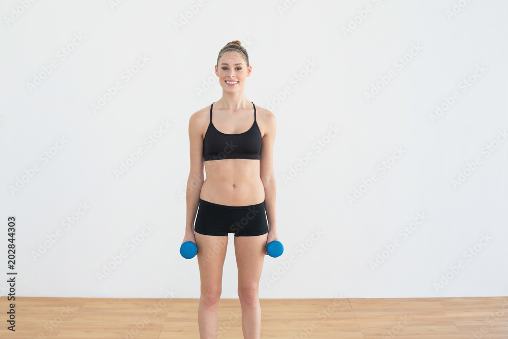 Proud fit woman posing holding some dumbbells