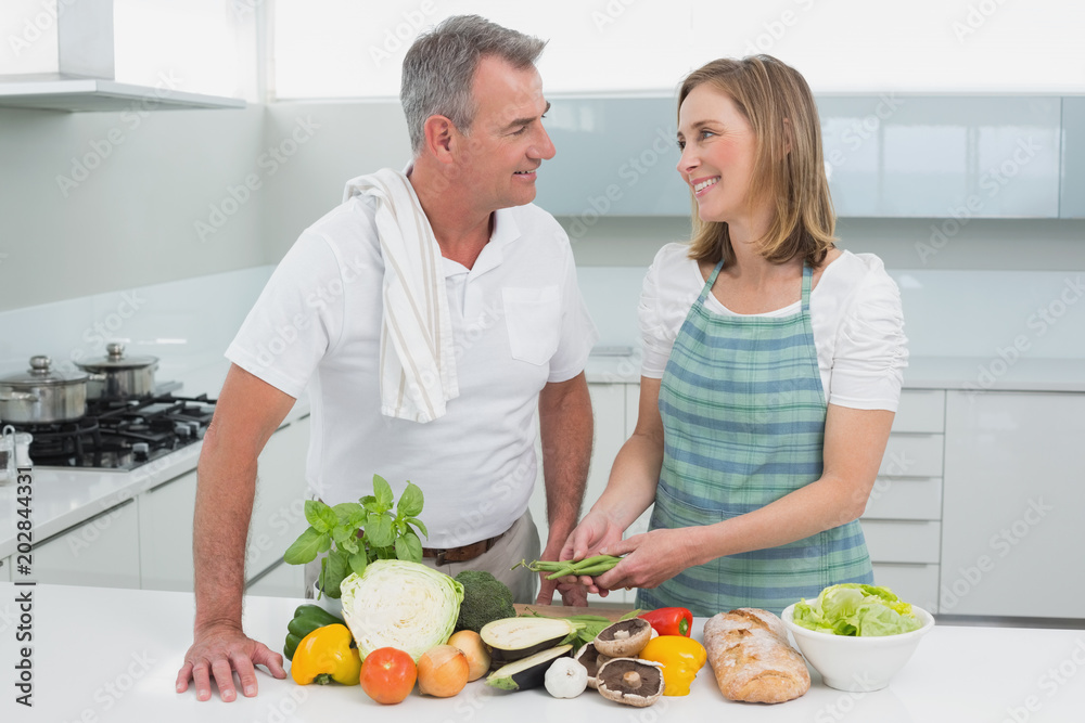 Happy couple preparing food together in kitchen Happy couple preparing food together in kitchen