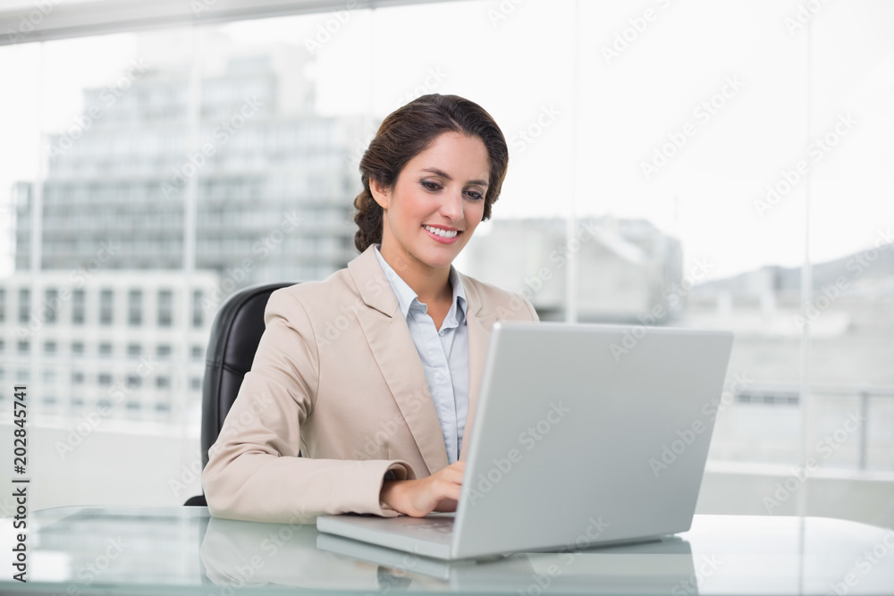Happy businesswoman typing on laptop at her desk Happy businesswoman typing on laptop at her desk