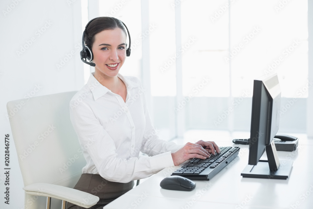 Businesswoman wearing headset while using computer Businesswoman wearing headset while using computer