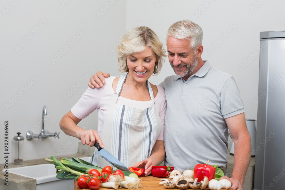 Happy mature couple preparing food together in kitchen Happy mature couple preparing food together in kitchen