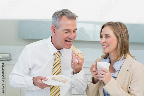Happy business couple having breakfast in kitchen