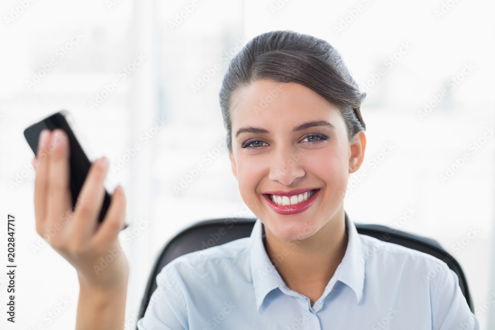 Content classy brown haired businesswoman holding a mobile phone Content classy brown haired businesswoman holding a mobile phone