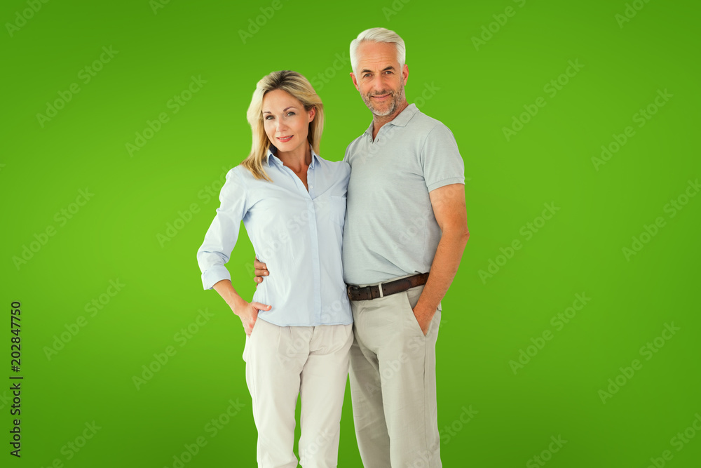 Happy couple standing and smiling at camera against green vignette Happy couple standing and smiling at camera against green vignette