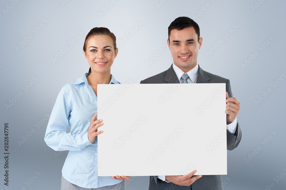 Business partners presenting sign against grey vignette Business partners presenting sign against grey vignette