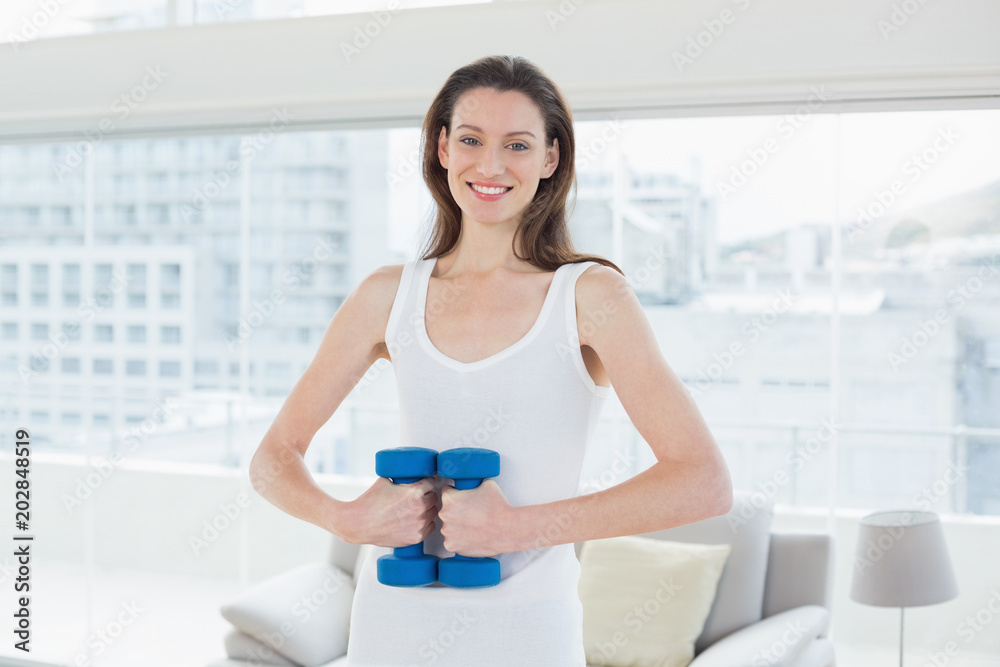 Fit woman exercising with dumbbells in fitness studio Fit woman exercising with dumbbells in fitness studio