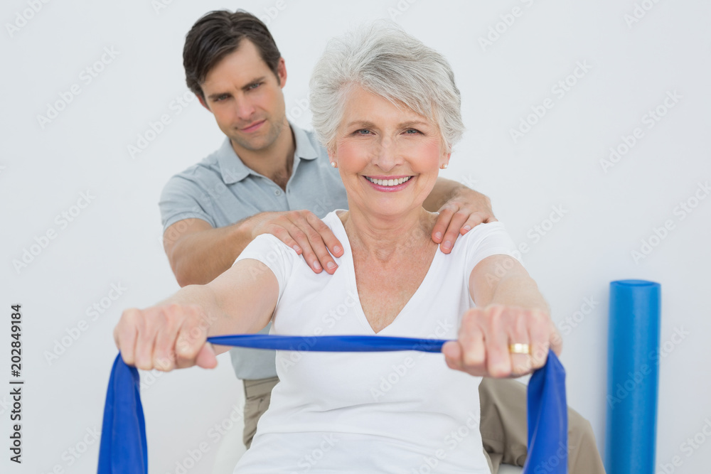 Male therapist assisting senior woman with exercises Male therapist assisting senior woman with exercises