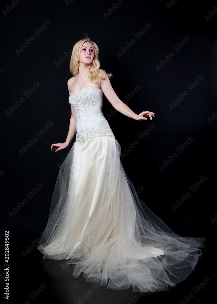 full length portrait of woman wearing white bridal gown. standing poison black studio background. full length portrait of woman wearing white bridal gown. standing poison black studio background.