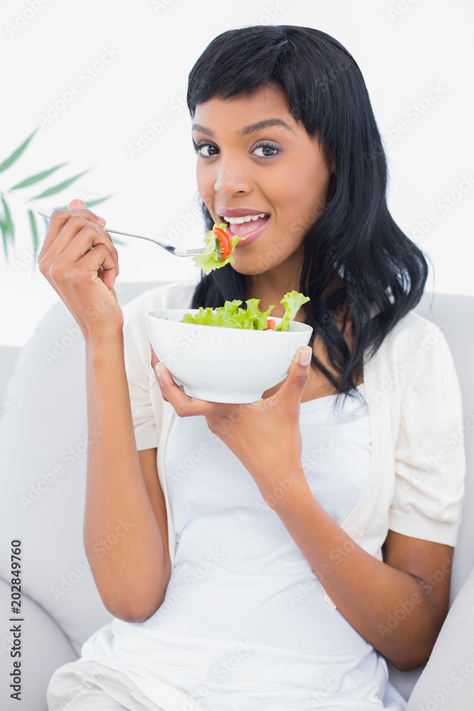 Calm black haired woman in white clothes eating salad Calm black haired woman in white clothes eating salad