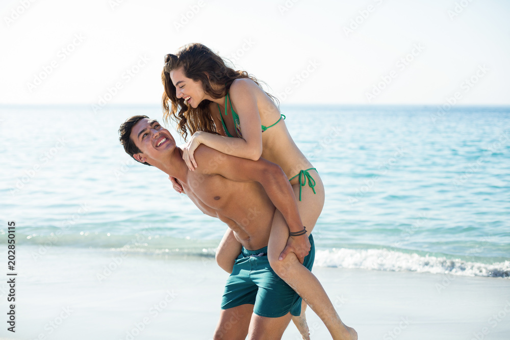 Boyfriend piggybacking girlfriend on shore
