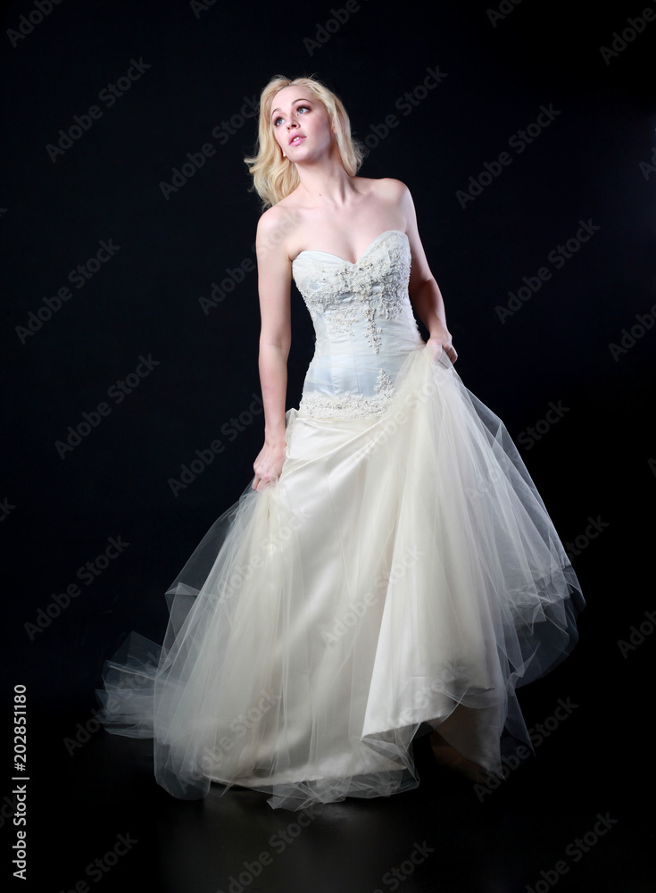 full length portrait of woman wearing white bridal gown. standing poison black studio background. full length portrait of woman wearing white bridal gown. standing poison black studio background.