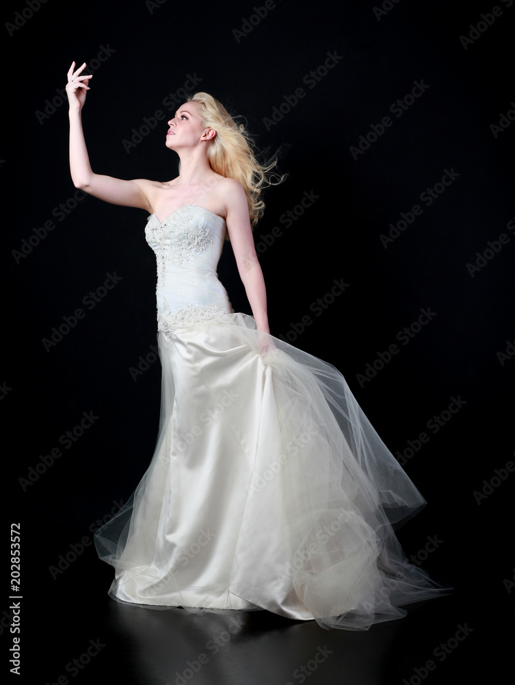 full length portrait of woman wearing white bridal gown. standing poison black studio background. full length portrait of woman wearing white bridal gown. standing poison black studio background.