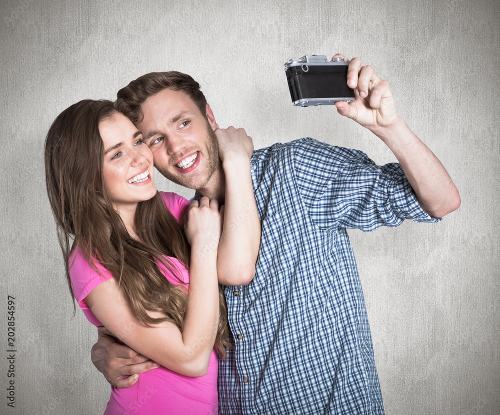 Couple taking selfie with digital camera against weathered surface Couple taking selfie with digital camera against weathered surface