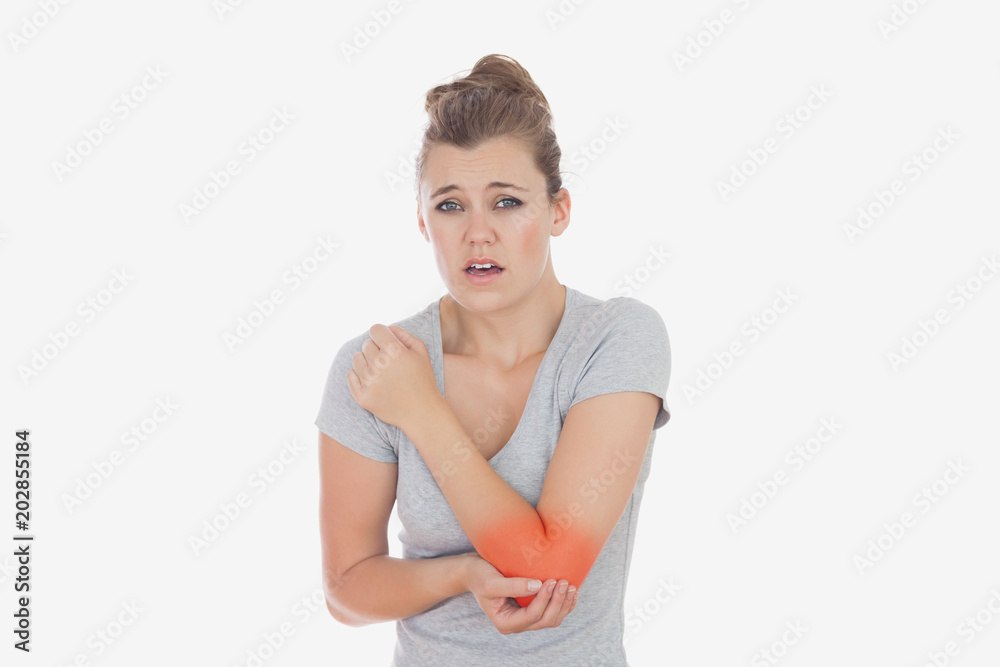 Portrait of young woman with elbow pain against white background Portrait of young woman with elbow pain against white background