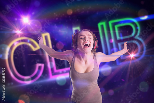 Pretty girl listening to music against digitally generated colourful club text