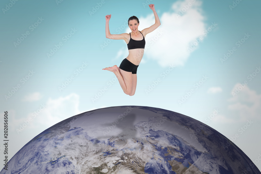 Full length of a sporty young woman jumping against blue sky