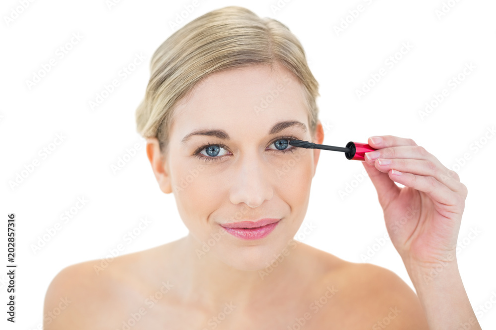 Fototapeta premium Smiling young blonde woman applying mascara