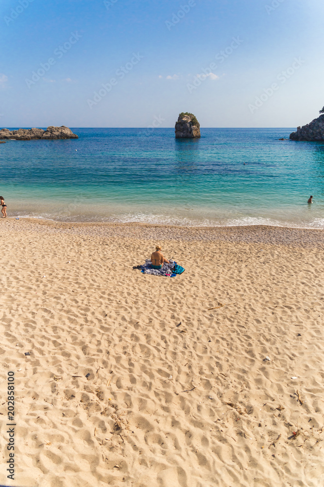 Obraz premium lady on the beach reading in parga greece