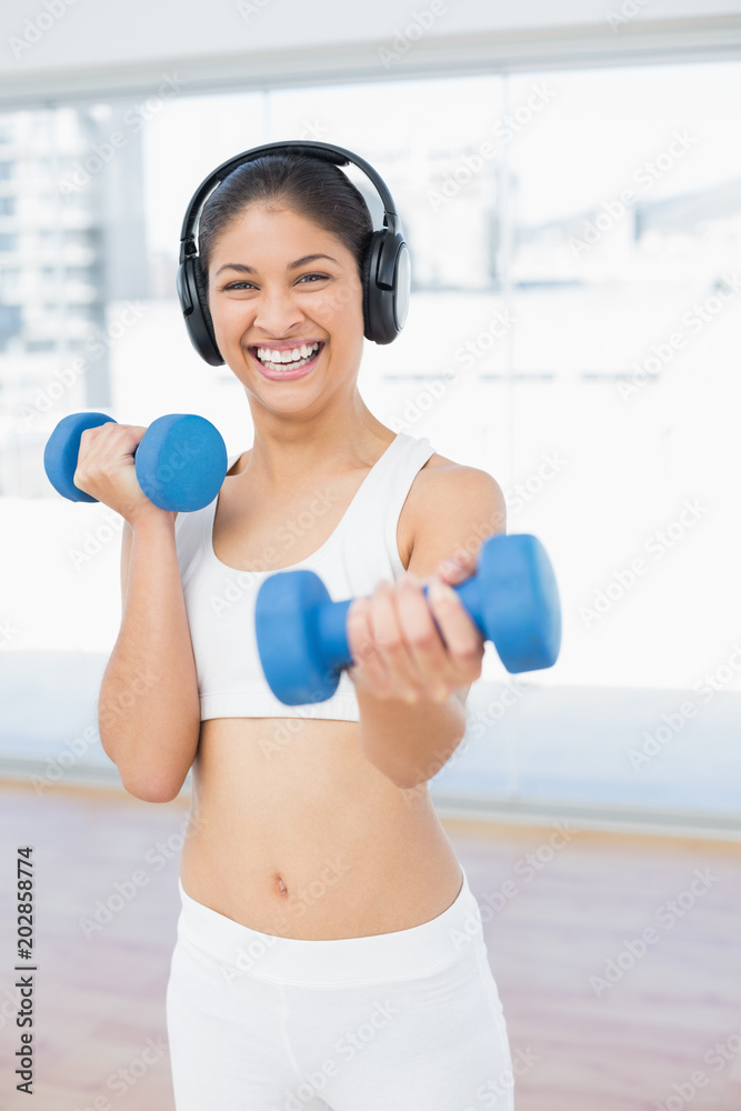 Cheerful woman exercising with dumbbells in fitness studio Cheerful woman exercising with dumbbells in fitness studio