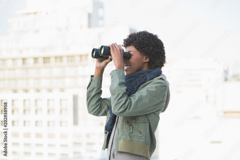 Cheerful casual model looking through binoculars Cheerful casual model looking through binoculars