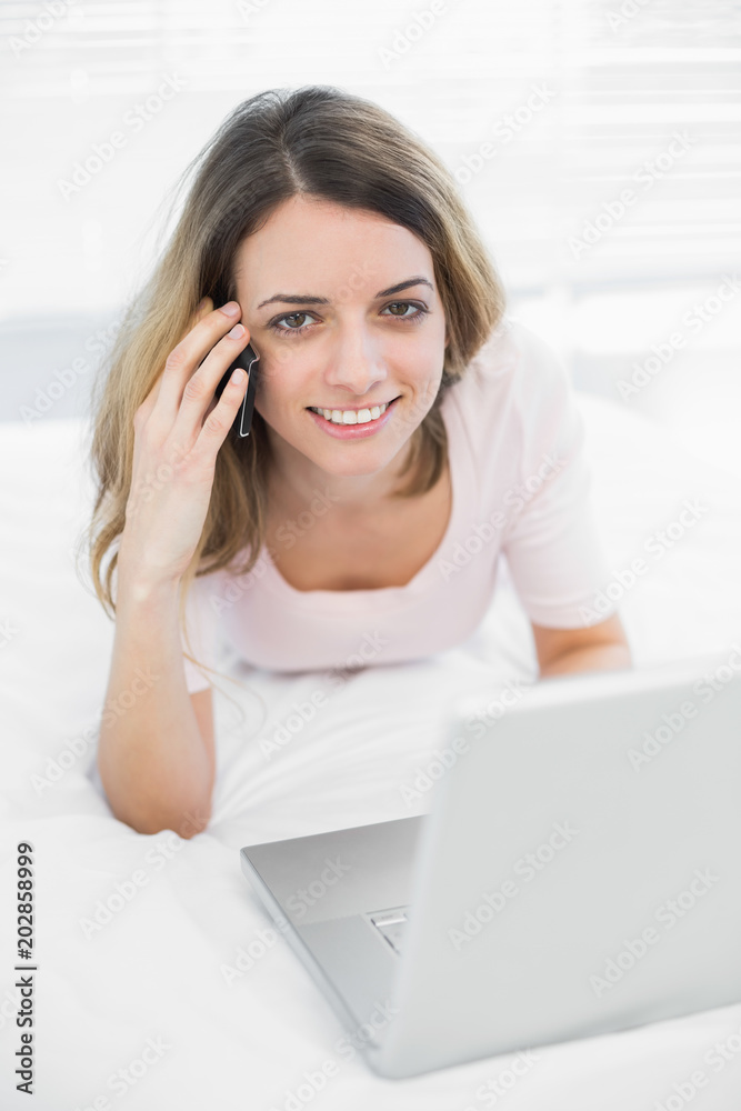 Pretty young woman phoning with her smartphone smiling at camera Pretty young woman phoning with her smartphone smiling at camera