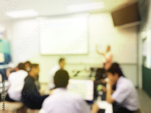 Blurred image of group of students are learning and sitting at desk using computer lap together in classroom for study and workshop in computers room at secondary school. education technology concept.