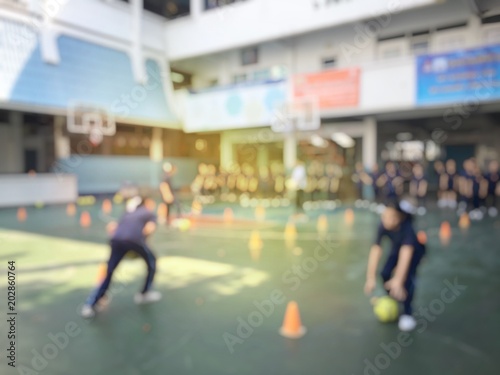 Blurred image of children or male and female students in secondary school are learning football or soccer on school playground in physical education time. Bangkok,Thailand. physical activities concept