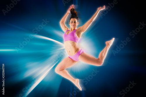 Fit brunette jumping and posing against abstract background