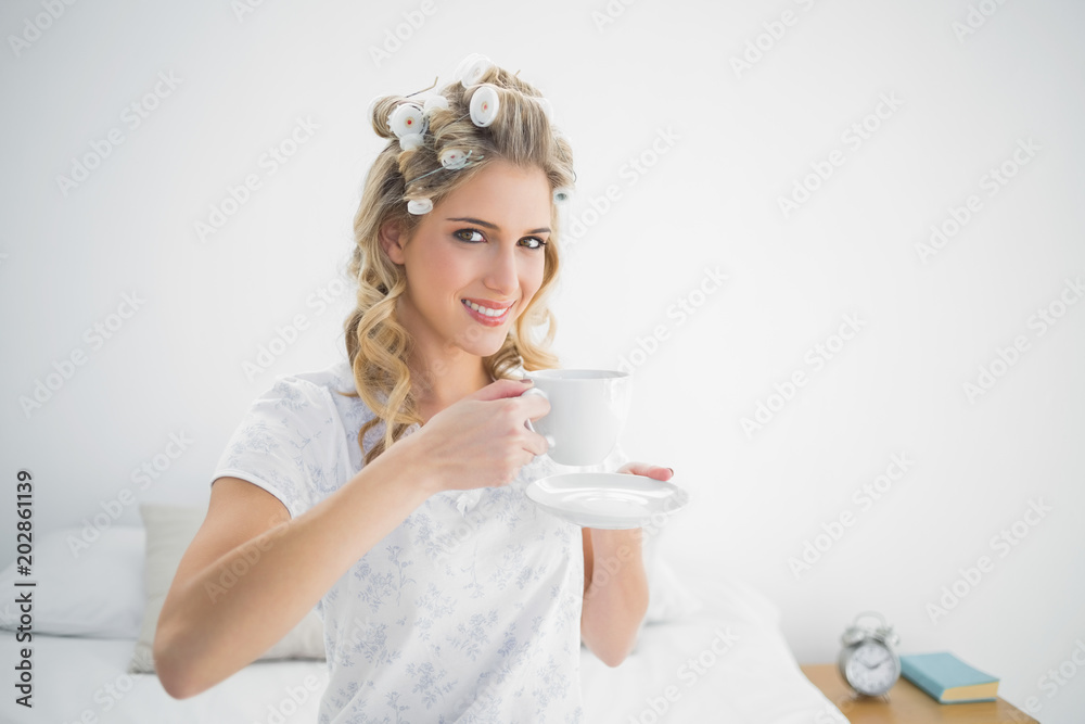Relaxed pretty blonde wearing hair curlers holding coffee Relaxed pretty blonde wearing hair curlers holding coffee