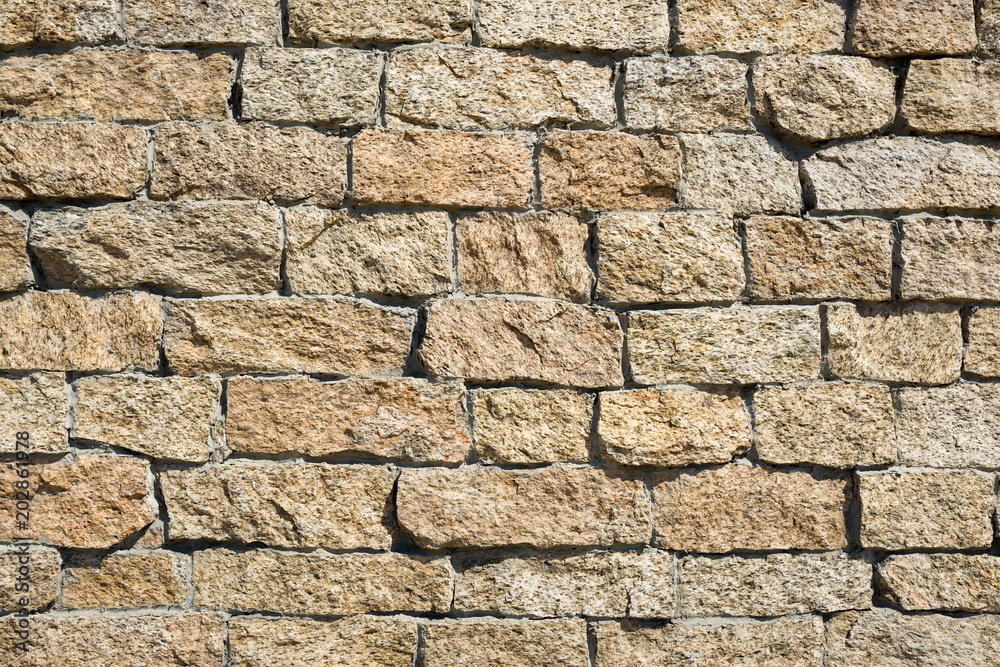 Wall made of crushed stone in the sunlight 