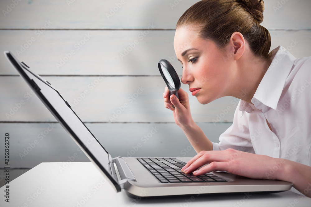 Φωτογραφία Attentive businesswoman typing on laptop against painted blue wooden planks