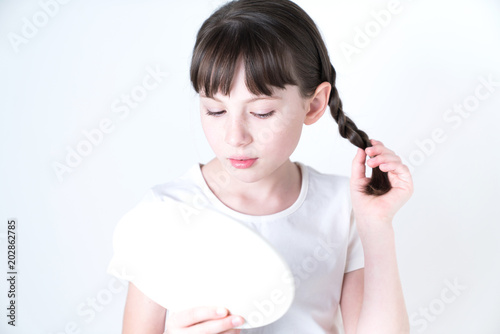 Petty girl checking her favial skin with a hand mirror. photo