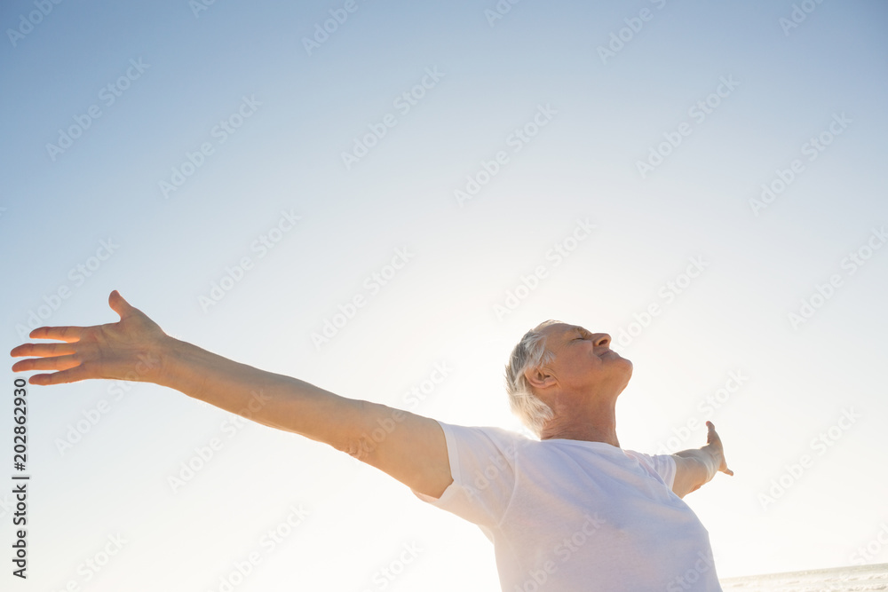 Active senior man with arms outstretched standing against clear sky