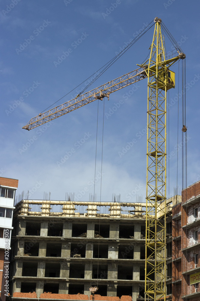 Crane and building under construction, against the blue sky