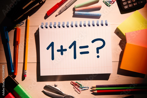 Composite image of one plus one against students desk