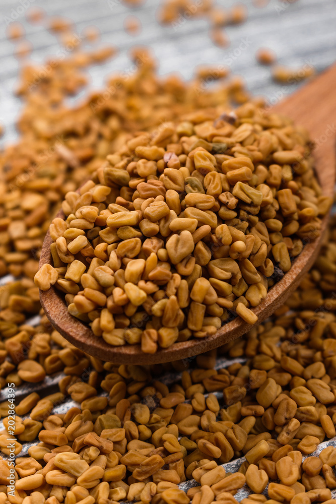 fragrant grains of fenugreek on a rustic background fragrant grains of fenugreek on a rustic background